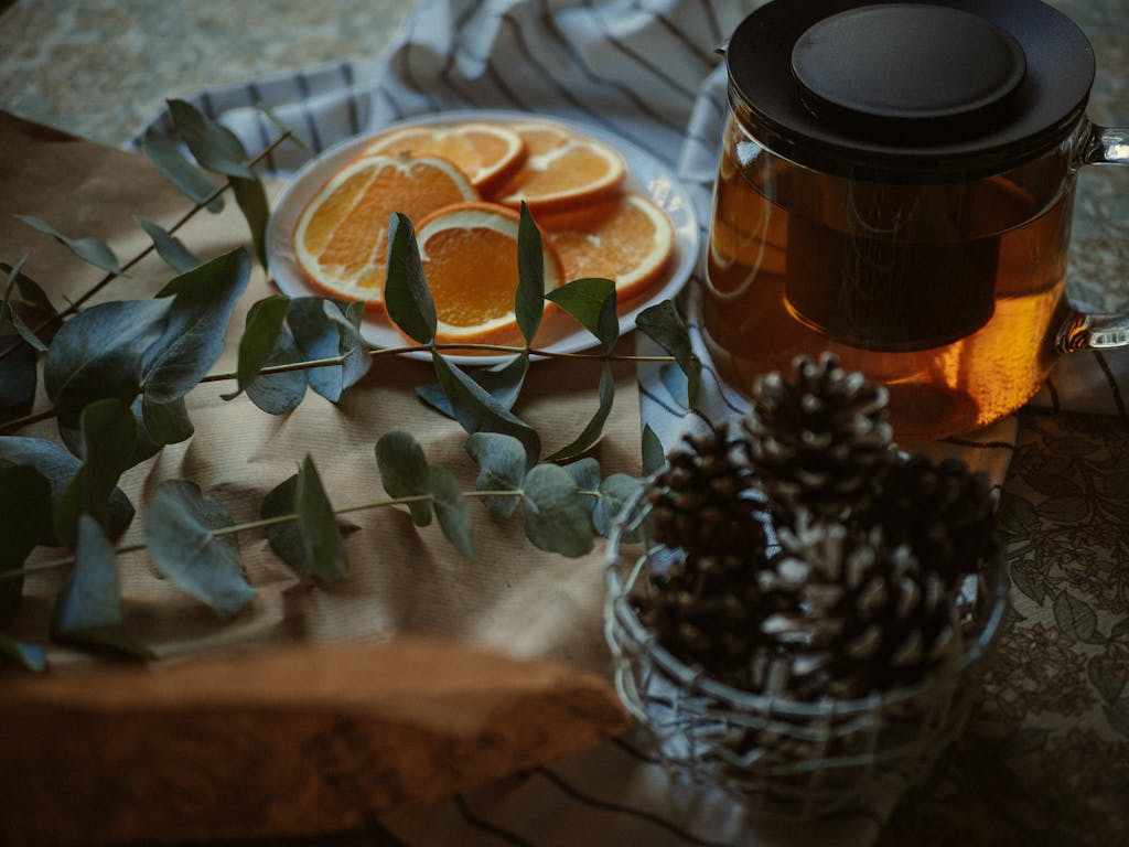 Orange Slices Beside a Jar of Honey and Bowl of Pine Cones